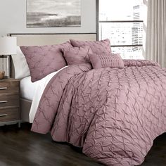 a bed with a purple comforter and pillows