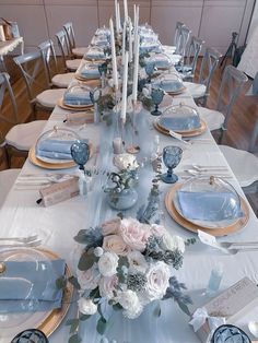 the table is set with blue and white dishes, silver place settings, and floral centerpieces