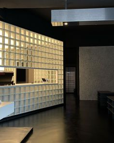 an empty room with glass blocks on the wall and tables in front of it at night