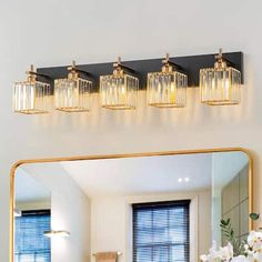 a bathroom vanity with a mirror and lights on the wall next to flowers in a vase