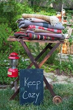 a sign sitting on top of a wooden stand in the grass next to a pile of blankets