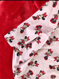 the mickey mouse blanket is laying on top of red velvet material, which has been folded over