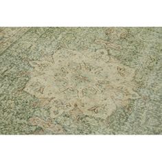 an antique rug with green and beige colors