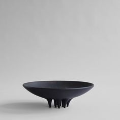 a black bowl sitting on top of a white table next to a gray wall and floor