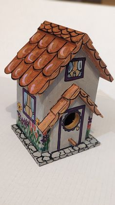 a paper model of a house with a birdhouse on the roof