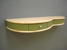 a green shelf with two drawers on the top and one drawer at the bottom, against a gray wall