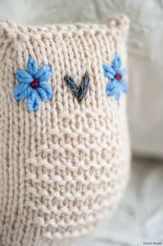 a knitted pillow with blue flowers on it