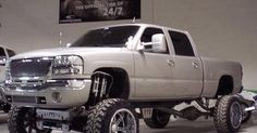 a silver truck parked in a garage next to other trucks and tires on the floor