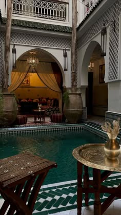 an indoor swimming pool with tables and chairs in the foreground, surrounded by arches