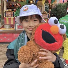 a child holding a stuffed animal in front of an amusement park