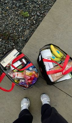 a person standing next to a bag full of food and snacks on the ground with their feet propped up