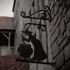 a sign on the side of a building with a silhouette of a witch holding a broom