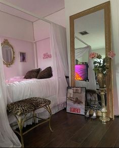 a bedroom with pink walls, leopard print foot stool and white canopy bed frame in the corner