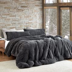 a bedroom with a large bed covered in grey blankets