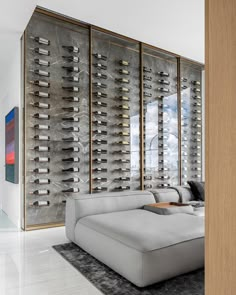 a large white couch sitting in front of a wall filled with wine bottles on it's side