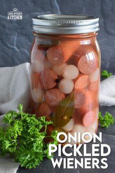 a jar filled with pickled wieners and parsley on top of a table