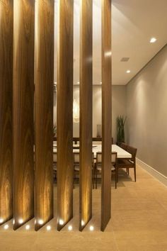 a room divider made out of wood with lights on each side and a dining table in the background