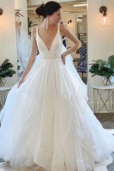 a woman in a white wedding dress looking at herself in the mirror with her hand on her hip