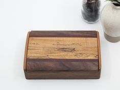 a wooden box sitting on top of a table next to a vase and potted plant