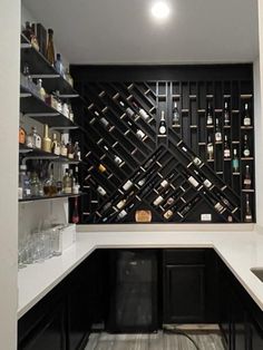 a wine rack in the corner of a kitchen with white counter tops and black cabinets