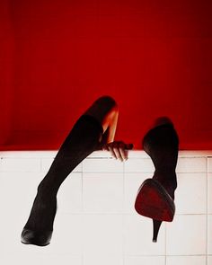 a woman's legs hanging off the side of a bath tub with red walls