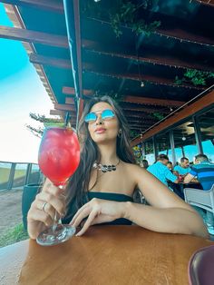 a woman sitting at a table with a drink in her hand