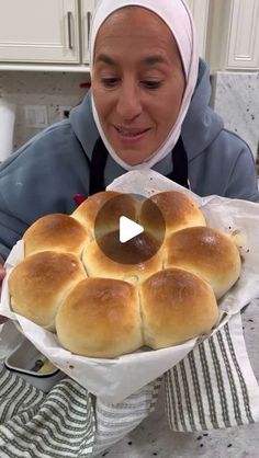 a woman holding a tray with rolls in it