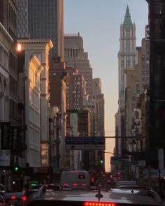 a city street filled with lots of traffic and tall buildings in the background at sunset