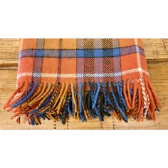 an orange and blue plaid blanket laying on top of a wooden floor