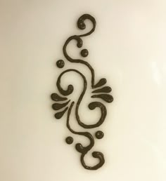 an intricately designed metal object on a white surface with black dots and swirls