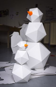 several white paper snowmen sitting on top of each other in the middle of a room