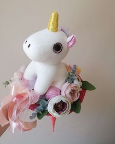 a stuffed unicorn is sitting on top of a bouquet of pink and white flowers with a gold horn