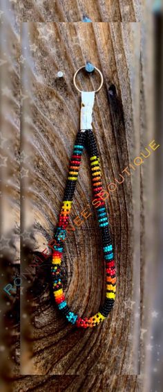 a multicolored beaded keychain hanging from a wooden piece with a metal hook