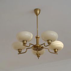 a chandelier hanging from the ceiling with five lights on each end and four shades off to the side