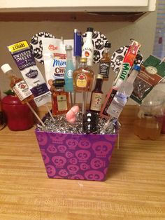 a purple basket filled with lots of liquor and other items on top of a wooden table