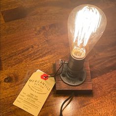 a light bulb sitting on top of a wooden table next to a paper with a tag