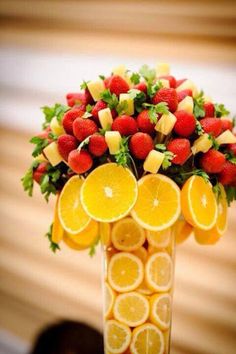 a vase filled with oranges and strawberries on top of a table