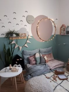 a bedroom decorated in pastel colors with lights on the wall and round mirror above it