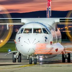 an airplane that is sitting on the tarmac at night with its lights on and it's wheels spinning in the air