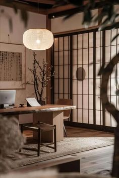 a room with a table, chair and laptop on the floor next to a tree