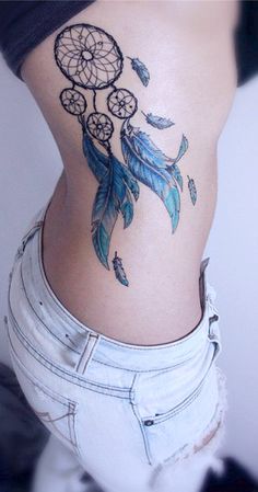 a woman's stomach with a tattoo on it that has a dream catcher and feathers