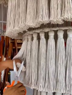 a woman is working on some tassels hanging from a rack in a shop