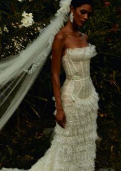 a woman in a wedding dress is posing for the camera with her veil blowing in the wind