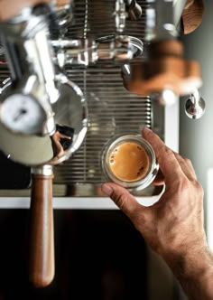 a man is holding a cup of coffee in front of an espresso machine