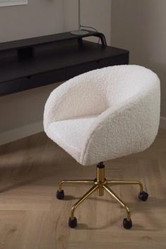 a white chair sitting on top of a wooden floor next to a desk and computer monitor