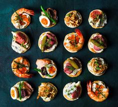 small appetizers are arranged in rows on a green tablecloth, including shrimp and praw