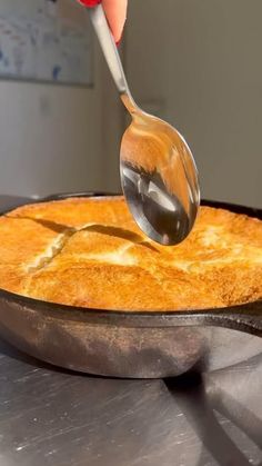 a person scooping something into a skillet with a spatula on top of it