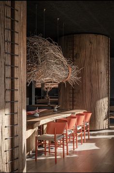 the dining room table is made out of wood and has orange chairs around it, along with a bird's nest chandelier