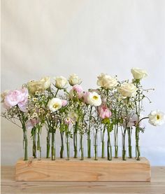 a bunch of flowers that are in some glass vases on a wooden stand with white and pink flowers