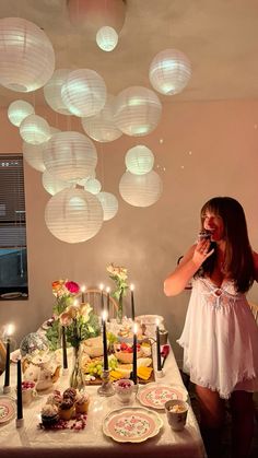 a woman standing in front of a table with plates and candles on top of it